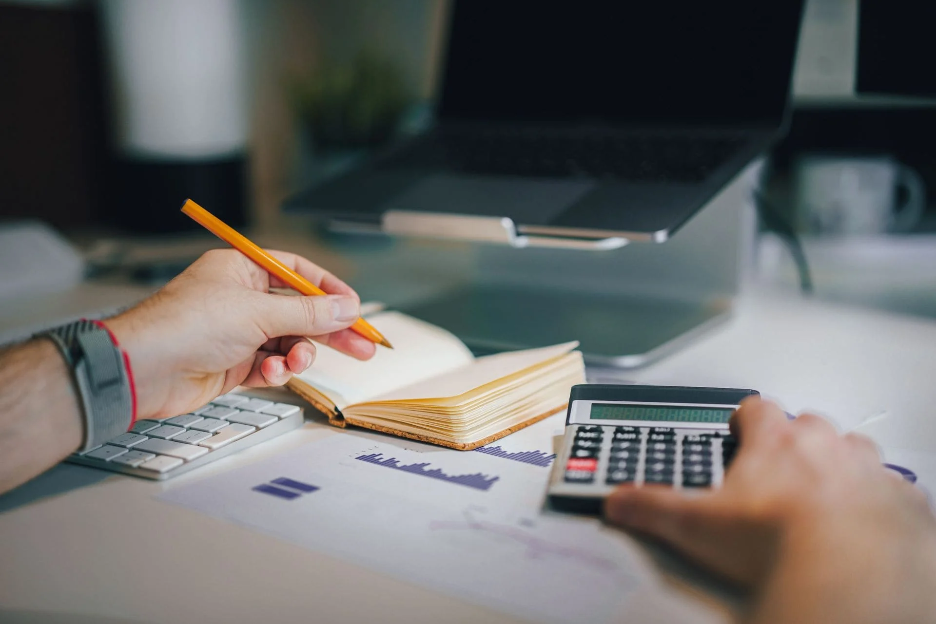 Persons hands working out how much a website costs using notepad and calculator